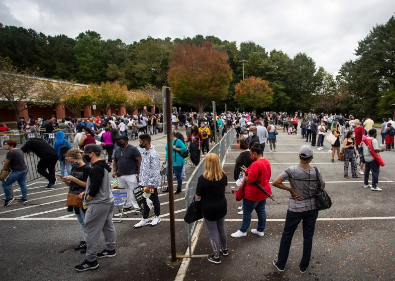 FILE - In this Oct. 12, 2020, file photo, hundreds of people wait in line for early voting in Marietta, Ga. The sweeping rewrite of Georgia's election rules that was signed into law by Republican Gov. Brian Kemp Thursday, March 25, 2021, represents the first big set of changes since former President Donald Trump's repeated, baseless claims of fraud following his presidential loss to Joe Biden. Georgia's new, 98-page law makes numerous changes to how elections will be administered, including a new photo ID requirement for voting absentee by mail. (AP Photo/Ron Harris, File)