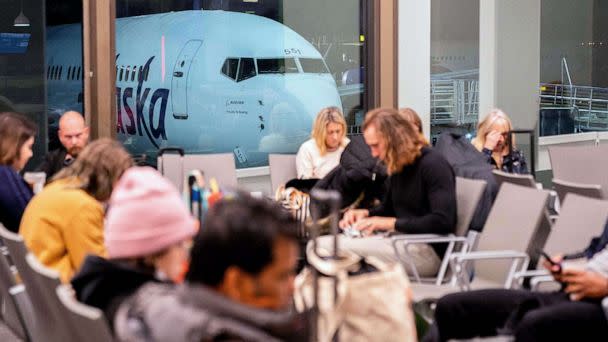 PHOTO: Travelers wait in the terminal as an Alaska Airlines plane sits at a gate at Los Angeles International Airport in Los Angeles, Jan. 11, 2023. (Stefani Reynolds/AFP via Getty Images)