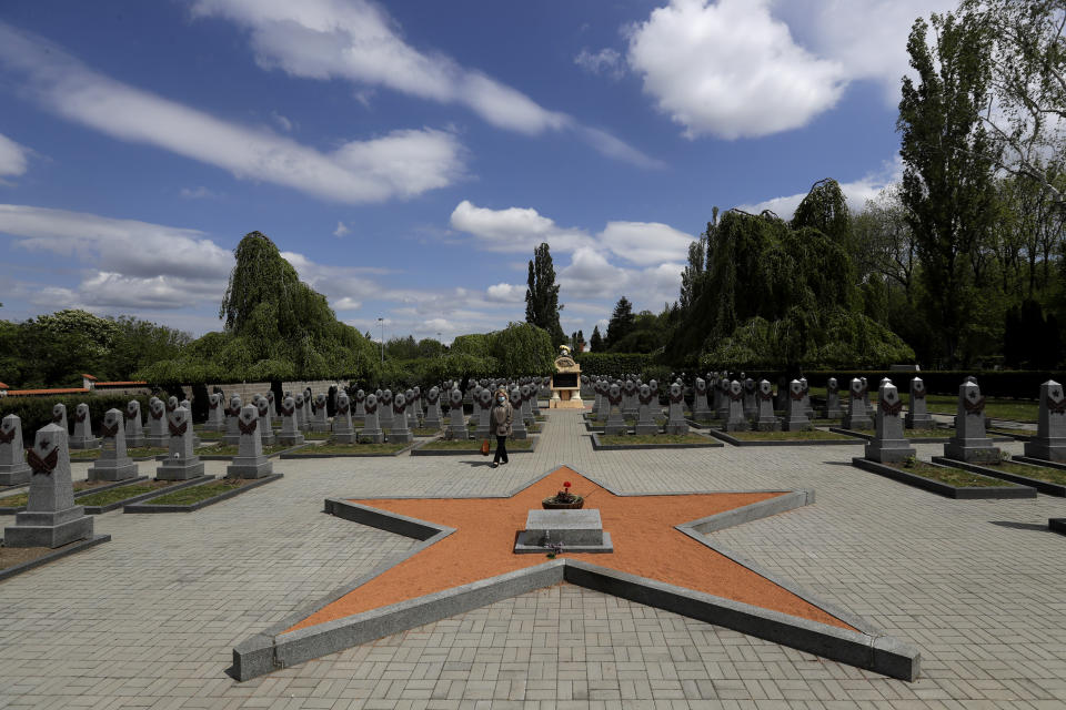 In this photo taken on Wednesday, May 6, 2020, a woman walks past tombstones at the Soviet World War II memorial in Prague, Czech Republic. Relations between the Czech Republic and Russia have taken a turn for the worse in a series of disputes over the interpretation of historical events. Three Prague politicians whose recent actions upset Russia have been placed under police protection amid a media report that Russian intelligence services have been plotting to poison them with the deadly toxin ricin. Russia has opened a criminal investigation into Prague's removal of a war memorial to a World War II hero, among other actions that have tested diplomatic ties. (AP Photo/Petr David Josek)