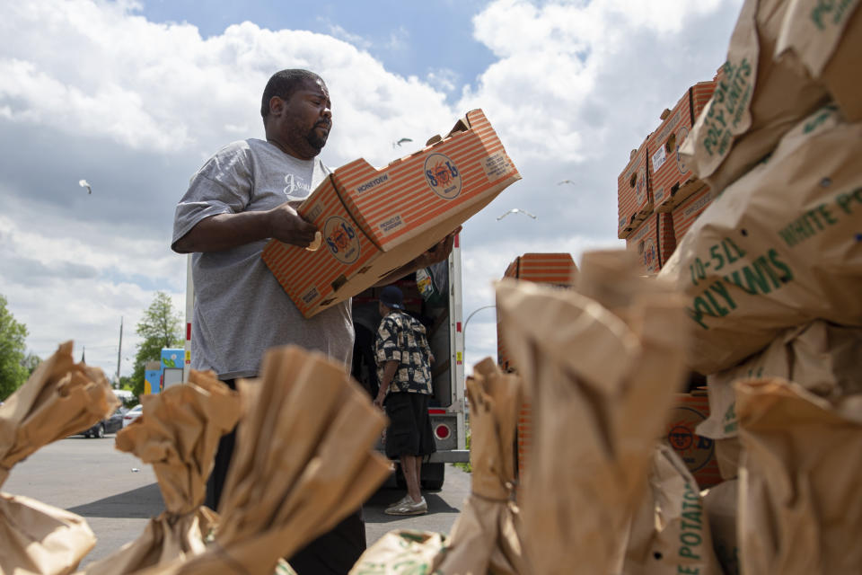 Pastor Andre Kamoche, with Rehoboth House of Prayer, helps unload a truck of fresh produce to be given out to people affected by the Tops Friendly Market closure, Tuesday, May 17, 2022, in Buffalo, N.Y. (AP Photo/Joshua Bessex)