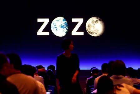 FILE PHOTO: A woman is seen in front of a sign reading Zozo, which operates Japan's popular fashion shopping site Zozotown, at an event in Tokyo launching the debut of its formal apparel items