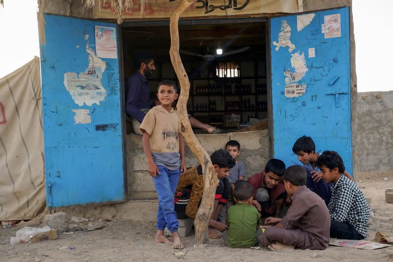 Boys play outside a shop at a makeshift camp for internally displaced people (IDPs) in the oil-producing Marib province