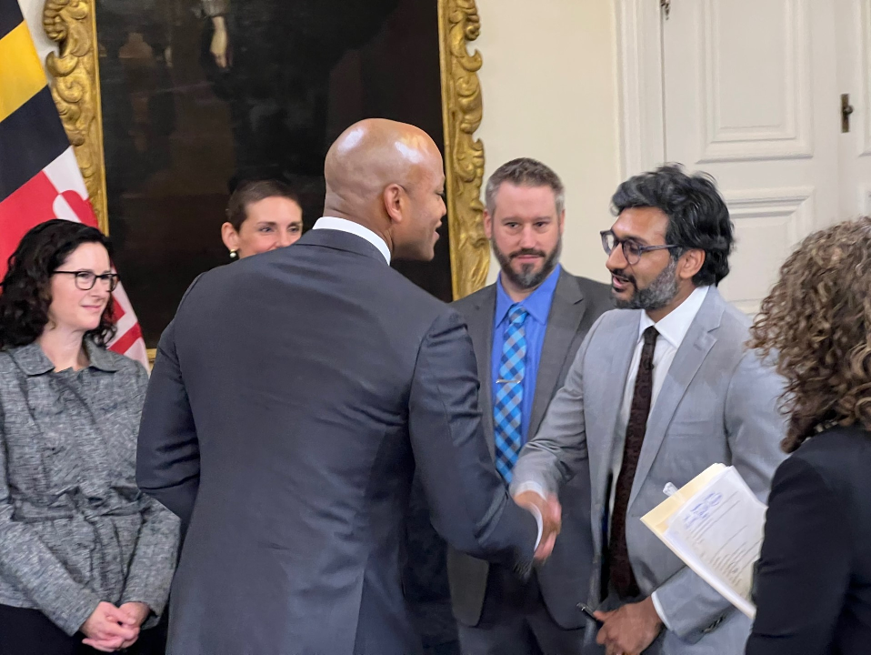 Maryland Gov. Wes Moore shakes the hand of Nishant Shah, the state's senior advisor for responsible artificial intelligence, after presenting him with a ceremonial pen used to sign an executive order on artificial intelligence in Annapolis on Jan. 8, 2024. Shah, who started work in state government last year, holds the pen in his left hand.