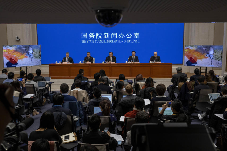 Shohrat Zakir, chairman of China's Xinjiang Uighur Autonomous Region, center and others look on as screens show a documentary titled "Fighting Terrorism in Xinjiang" during a press conference in Beijing on Monday, Dec. 9, 2019. (AP Photo/Ng Han Guan)