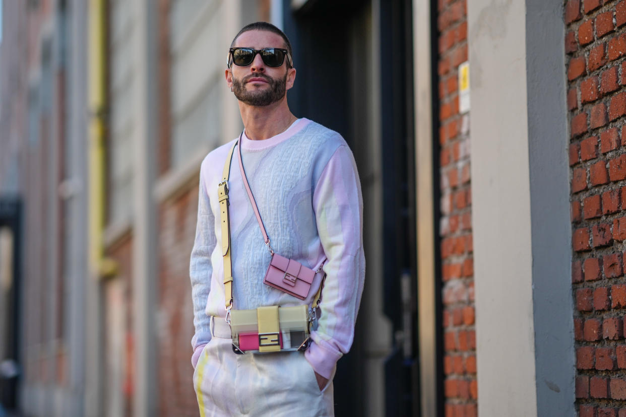 MILAN, ITALY - JANUARY 15: Pelayo Díaz wears sunglasses from Ray Ban, a pastel color tie-and-dye pink yellow and blue pullover / sweater with embossed and texture Fendi logo / monograms, a mini Fendi pink bag, a multi pastel colored Fendi bag, matching tie-and-dye pastel colored trousers / pants, outside the Fendi fashion show during the Milan Men's Fashion Week - Fall/Winter 2022/2023 on January 15, 2022 in Milan, Italy. (Photo by Edward Berthelot/Getty Images)