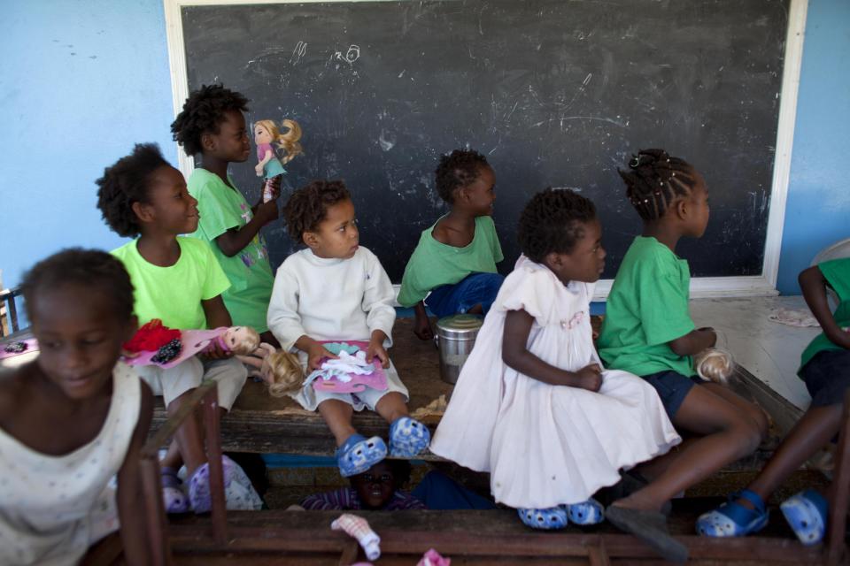 In this Feb. 1, 2014 photo, children play as they watch a worker enter their orphanage run by the U.S. Church of Bible Understanding in Kenscoff, Haiti. The Church of Bible Understanding lost accreditation to run their orphanage after a series of inspections beginning in November 2012, but the government lacks the resources to shut down homes except in extreme circumstances. (AP Photo/Dieu Nalio Chery)