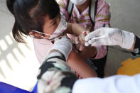 A young girl held by her mother pushes a shaft of a needle as she receives a first dose of Sinovac's COVID-19 vaccine at a health center outside Phnom Penh, Cambodia on Wednesday, Feb. 23, 2022. Cambodia began vaccinating 3- and 4-year-olds with Chinese-made Sinovac shots Wednesday after finding young children accounting for many new infections. Prime Minister Hun Sen appealed for parents to get their children vaccinated as soon as they can. (AP Photo/Heng Sinith)