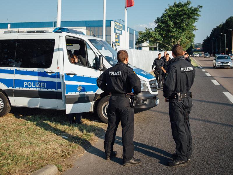 Polizisten bewachen die Einfahrt zum Parkplatz vor dem ehemaligen Praktiker-Baumarkt in Heidenau (Sachsen), wo jetzt Flüchtlinge untergebracht werden. Foto: Oliver Killig