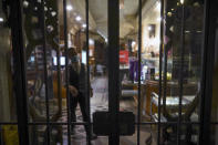 A staffer stands behind the bars of a closed restaurant, in Rome, Monday, Oct. 26, 2020. For at least the next month, people outdoors except for small children must now wear masks in all of Italy, gyms, cinemas and movie theaters will be closed, ski slopes are off-limits to all but competitive skiers and cafes and restaurants must shut down in early evenings, under a decree signed on Sunday by Italian Premier Giuseppe Conte, who ruled against another severe lockdown despite a current surge in COVID-19 infections. (AP Photo/Andrew Medichini)