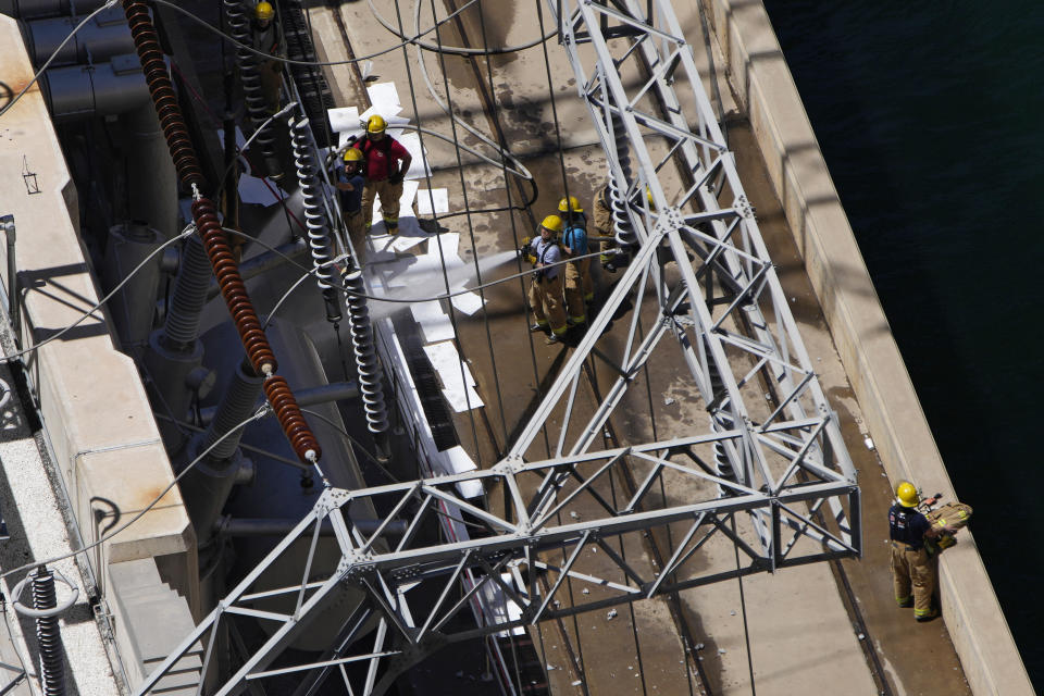 Firefighters spray water after a fire on the Arizona side of the Hoover Dam, Tuesday, July 19, 2022, near Boulder City, Nev. Officials say no one was injured when a transformer at Hoover Dam briefly caught fire Tuesday morning. (AP Photo/John Locher)