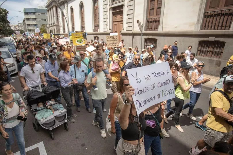 A protester holds a sign reading 'I have nowhere to go when my earth will be destroyed' during a demonstration to demand a tourism model respectful for the islands environment and their residents, on the Canary Island of Tenerife, on April 20, 2024