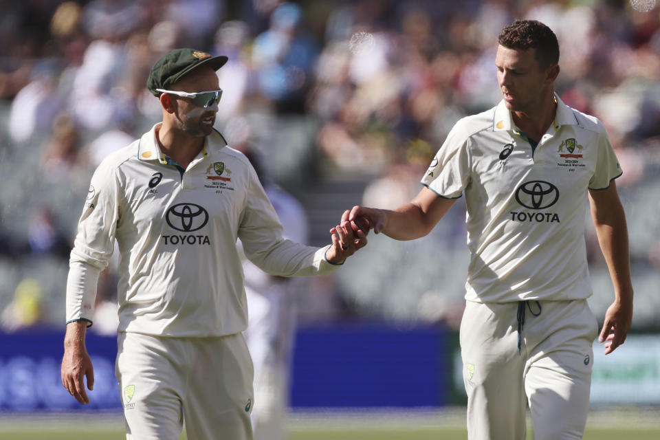 Australia's Nathan Lyon, left, hands the ball to teammate Josh Hazlewood on the second day of their cricket test match against the West Indies in Adelaide, Australia, Thursday, Jan. 18, 2024. (AP Photo/James Elsby)