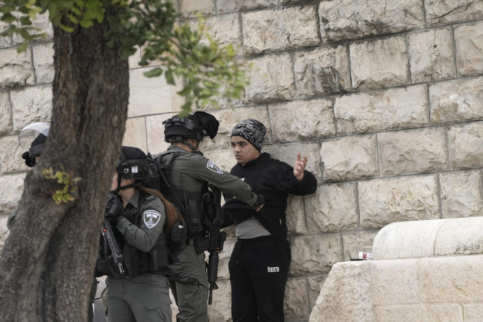 An Israeli Border Police officer searches a Palestinian teen outside of the Al-Aqsa Mosque compound in Jerusalem's Old City ahead of Friday prayers, Friday, Feb. 23, 2024. Many worshippers were not allowed in and prayed outside instead. (AP Photo/Mahmoud Illean)