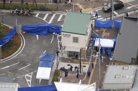 An aerial view shows police officers investigating the site where a police officer was found stabbed in front of a police box and the officer's gun, loaded with several bullets, was stolen, in Suita, Osaka