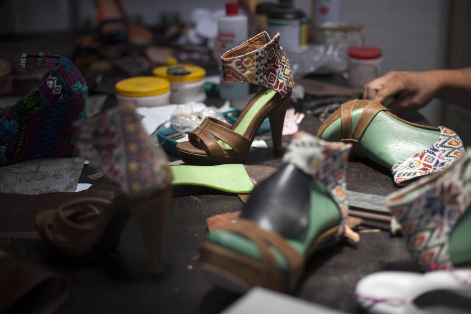 In this Aug, 21, 2013 photo, handmade shoes designed by Karim Corzo lay scattered on a workshop table at a factory in Guatemala City. Embroidered Mayan textiles known as huipiles are undergoing a revival in some of the country’s finest boutiques as they become a haute couture fixture. Young Guatemalan designers are using them for everything from evening gowns and purses to handmade shoes sold as far away as Dubai. (AP Photo/Luis Soto)