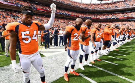 Oct 1, 2017; Denver, CO, USA; Denver Broncos inside linebacker Brandon Marshall (54) and free safety Darian Stewart (26) and cornerback Aqib Talib (21) and cornerback Chris Harris Jr. (25) react along with teammates during the American national anthem before a game against the Oakland Raiders at Sports Authority Field at Mile High. Mandatory Credit: Ron Chenoy-USA TODAY Sports