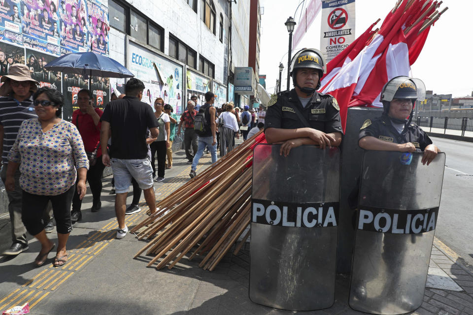 Police stand guard as people walk in a line to attend the wake of Peru's late President Alan Garcia at his political party's headquarters in Lima, Peru, Thursday, April 18, 2019. Garcia shot himself in the head and died Wednesday as officers waited to arrest him in a massive graft probe that has put the country's most prominent politicians behind bars and provoked a reckoning over corruption. (AP Photo/Martin Mejia)