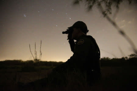 A border patrol agent uses night vision goggles to look for immigrants who illegally crossed the border from Mexico into the U.S. in the Rio Grande Valley sector, near McAllen, Texas, U.S., April 2, 2018. REUTERS/Loren Elliott