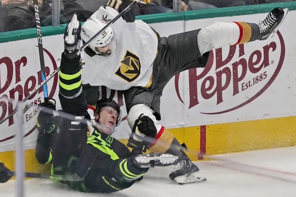 Dallas Stars defenseman Esa Lindell (23) is knocked down by Vegas Golden Knights center Nicolas Roy (10) during the second period of an NHL hockey game in Dallas, Saturday, April 8, 2023. (AP Photo/LM Otero)