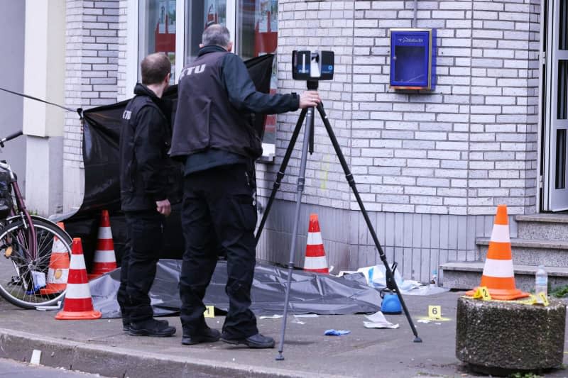 Two men secure traces and evidence next to a covered corpse outside a pub in Düsseldorf. One person was killed by gunfire in Duesseldorf on the early hours of 28 April. David Young/dpa