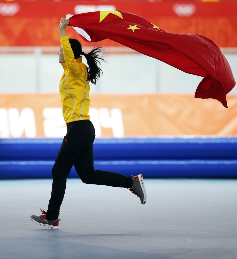 Gold medallist China's Zang Hong holds her national flag and runs in celebration after the women's 1,000-meter speedskating race at the Adler Arena Skating Center during the 2014 Winter Olympics in Sochi, Russia, Thursday, Feb. 13, 2014. (AP Photo/Pavel Golovkin)