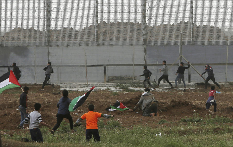 Protesters throw stones at the fence of Gaza Strip border with Israel, marking first anniversary of Gaza border protests east of Gaza City, Saturday, March 30, 2019. Tens of thousands of Palestinians on Saturday gathered at rallying points near the Israeli border to mark the first anniversary of weekly protests in the Gaza Strip, as Israeli troops fired tear gas and opened fire at small crowds of activists who approached the border fence. (AP Photo/Adel Hana)