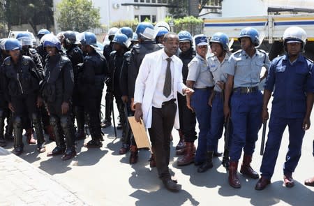 A doctor gestures as he speaks to Police officers during a doctors protest over the disappearance of the leader of their union in Harare