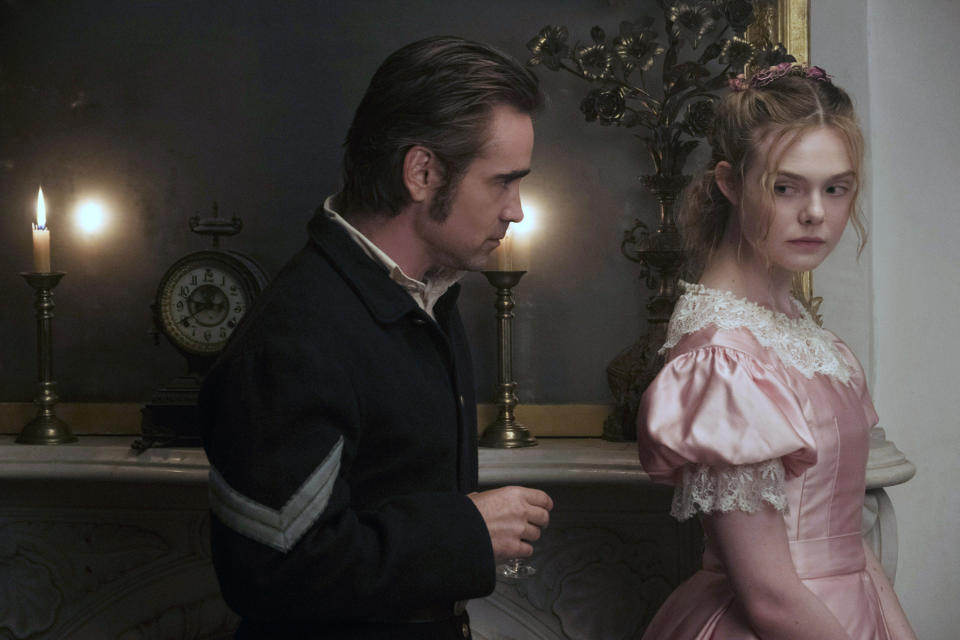 Elle Fanning stands in an 1800s pink ballgown; a man is standing behind her; she glances at him
