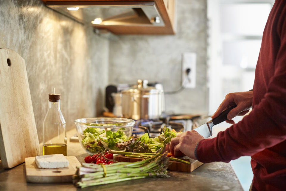 Midsection of man cutting vegetables. Cropped image of male is preparing food. He is working in kitchen.