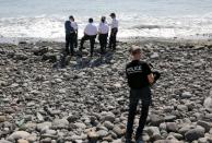 Police officers inspect debris found on a beach in Saint-Denis on Reunion Island in the Indian Ocean on August 2, 2015