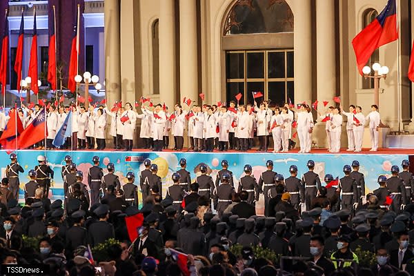 「中華民國一一一年元旦總統府升旗典禮」昨（一）日舉行，醫護人員揮舞國旗，上台領唱國歌，與民眾共同迎接新的一年。（圖：中央社）