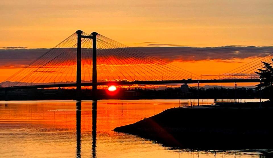 The sun rises behind the cable bridge and Clover Island in Kennewick. The bridge was a design sensation when it opened in 1978. Replacing tired lights with a dynamic LED system could make it one again, proponents say.