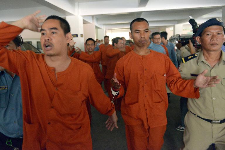 A group of Cambodian men are being escorted by police officers at the Phnom Penh Municipal court on April 11, 2014 after being convicted for allegedly planning to overthrow the government