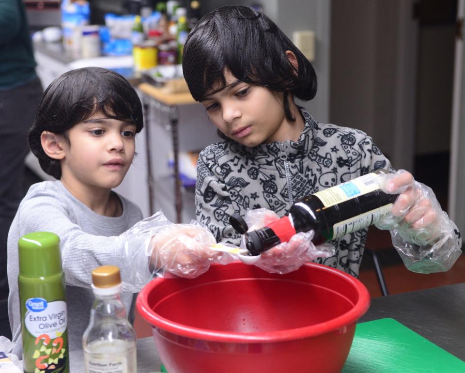 Andrew Pulivarthy, 6, gets an assist with soy sauce from Ashton Pulivarthy, 10, as they prepare Beef Lo Mein on Friday, Feb. 9, 2024, during a Youth and Parent Cooking Class at the Family Matters Resource Center.