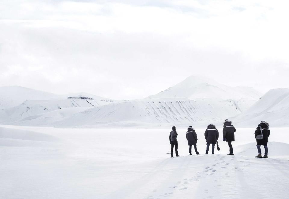 Arctic landscape with five people wearing outerwear.