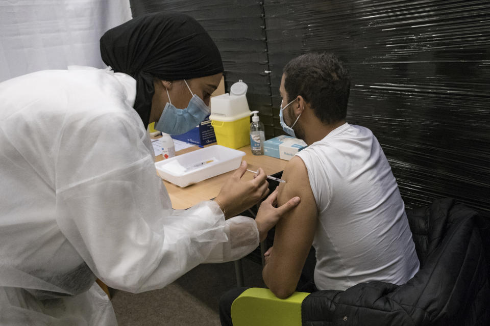 A nurse administrates the Pfizer COVID-19 vaccine to Thibaut Razafinarivo, 26, in a vaccination center in Versailles, west of Paris, Tuesday, July 13, 2021. More than 1 million people in France made vaccine appointments in less than a day, according to figures released Tuesday, after the president cranked up pressure on everyone to get vaccinated to save the summer vacation season and the French economy. (AP Photo/Constantin Gouvy)
