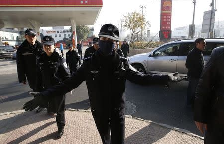 A female police gestures as she asks journalists to leave from the vicinity of the courthouse where the closed-door trial of Gao Yu is being held in Beijing November 21, 2014. REUTERS/Kim Kyung-Hoon