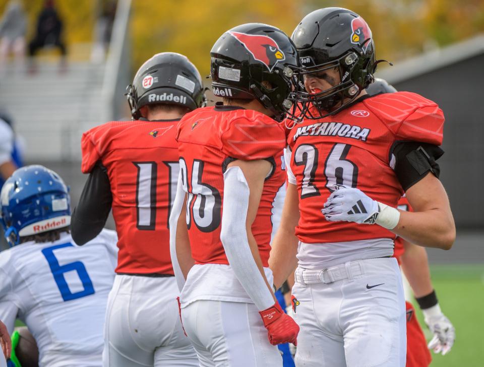 Metamora's Cameron Nickel (26) and teammate Eden Cote share a moment after a tackle against Decatur MacArthur in the first half of their Class 5A first-round state football playoff game Saturday, Oct. 28, 2023 in Metamora.