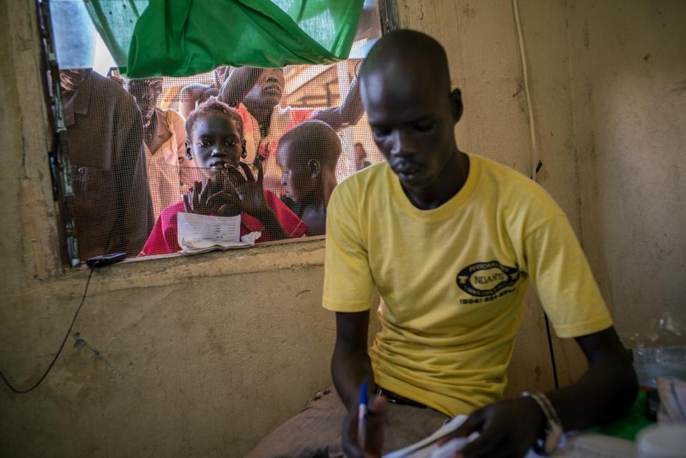 A man is seen at a window as patients stand outside.