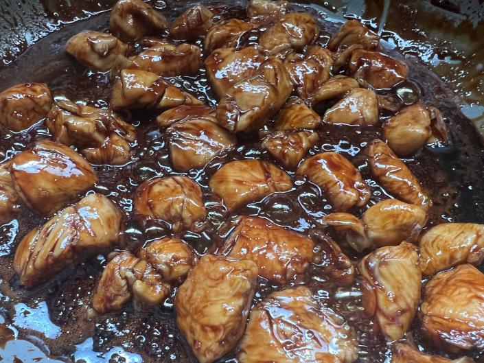 pieces of chicken cooking in teriyaki sauce in pan