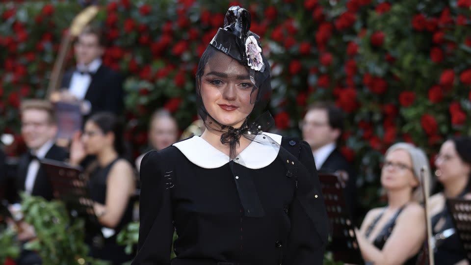 Maisie Williams wore a Maison Margiela outfit consisting of a delicate helmet-like mesh fascinator and a black mini dress with Peter Pan collar and cut-off fishnet tights. - Mike Marsland/WireImage/Getty Images
