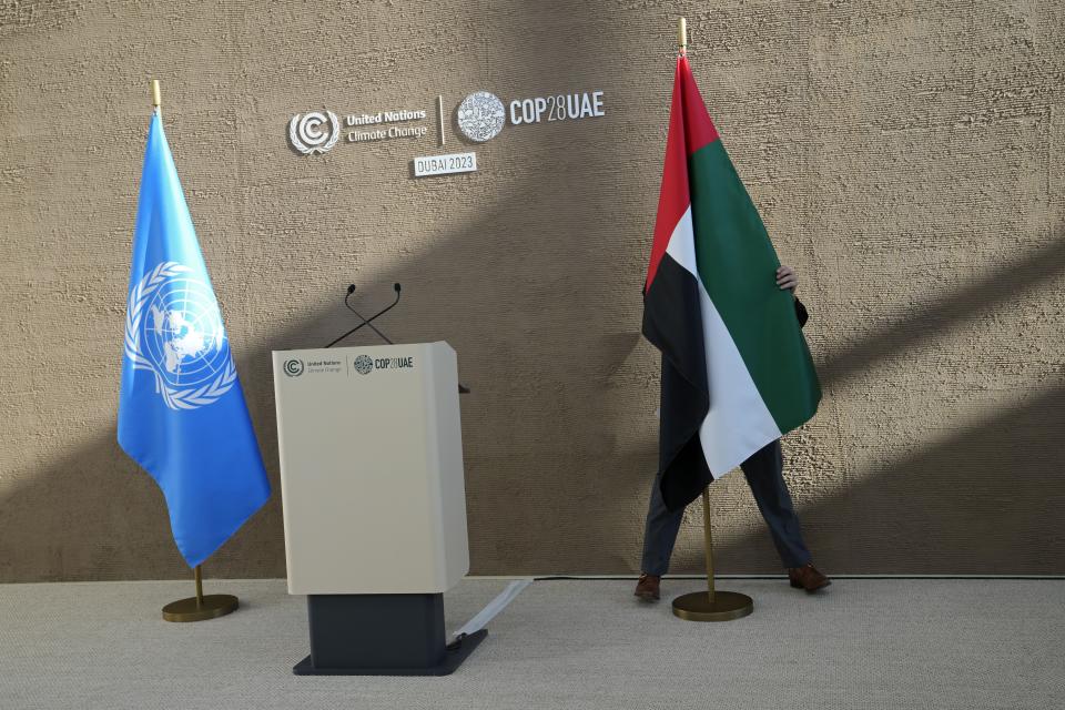 Una persona recoloca la bandera de Emiratos Árabes Unidos antes de una conferencia de prensa del responsable de clima de Naciones Unidas, Simon Stiell, en la cumbre COP28 de la ONU el lunes 11 de diciembre de 2023 en Dubái, Emiratos Árabes Unidos. (AP Foto/Kamran Jebreili)