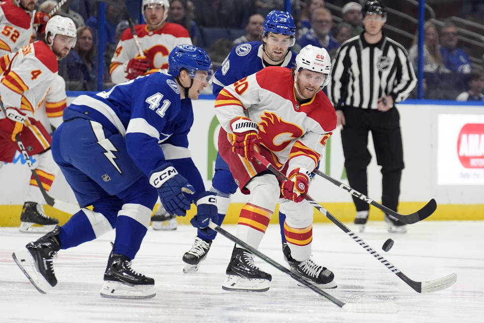 Calgary Flames center Blake Coleman (20) flips the puck past Tampa Bay Lightning right wing Mitchell Chaffee (41) during the first period of an NHL hockey game Thursday, March 7, 2024, in Tampa, Fla. (AP Photo/Chris O'Meara)