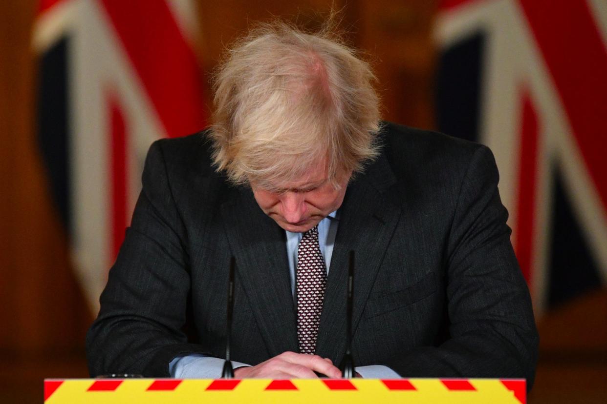  Boris Johnson looks down at the podium during a media briefing after the UK recorded 100,000 coronavirus deaths (PA)