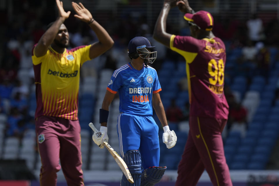 India's Axar Patel walks off the field as West Indies' bowler West Indies' Obed McCoy, left, and Jason Holder celebrate his dismissal during their first T20 cricket match at the Brian Lara Stadium in Tarouba, Trinidad and Tobago, Thursday, Aug. 3, 2023. (AP Photo/Ramon Espinosa)