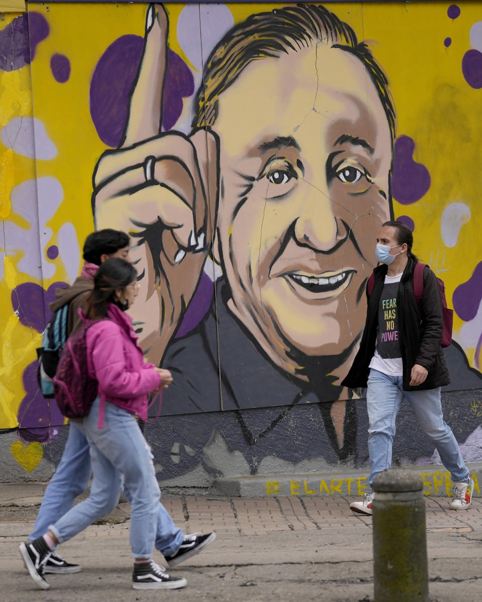 People walk past a campaign mural of presidential candidate Rodolfo Hernandez, with the Anti-corruption Governors League, in Bogota, Colombia, Friday, May 20, 2022. Elections are set for May 29. (AP Photo/Fernando Vergara)