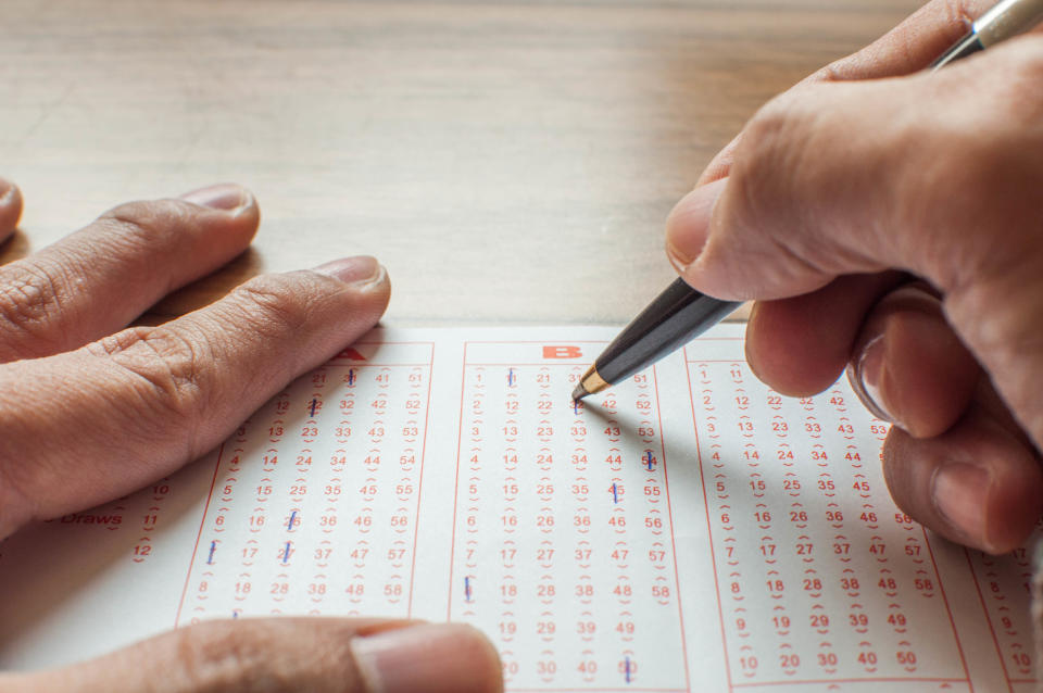 Close up of hands filling up a lottery ticket form a concept of gambling