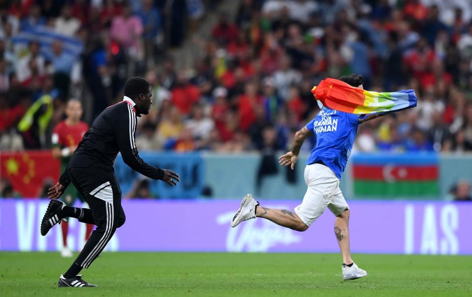 A pitch invader wearing a shirt reading "Respect for Iranian woman" holds a rainbow flag during the FIFA World Cup Qatar 2022 Group H match between Portugal and Uruguay at Lusail Stadium on November 28, 2022 in Lusail City, Qatar - Justin Setterfield/Getty Images