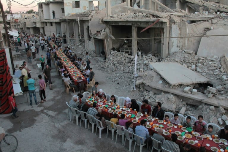 Syrian residents of the rebel-held town of Douma on the outskirts of Damascus break their fast with the "iftar" meal on a heavily damaged street on June 18, 2017, during the Muslim holy month of Ramadan