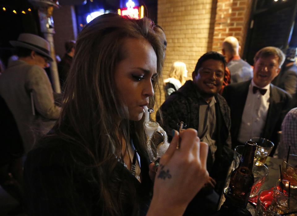 FILE - In this Dec. 31, 2013 file photo, partygoers smoke marijuana during a Prohibition-era themed New Year's Eve invite-only party celebrating the start of retail pot sales, at a bar in Denver. Colorado is on the brink of becoming the first state with licensed pot clubs. Denver officials are working on regulations to open a one-year pilot of bring-your-own marijuana clubs. (AP Photo/Brennan Linsley, file)